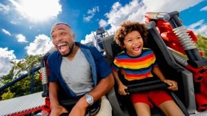 A father and a son on a roller coaster under a blue sky at LEGOLAND Florida